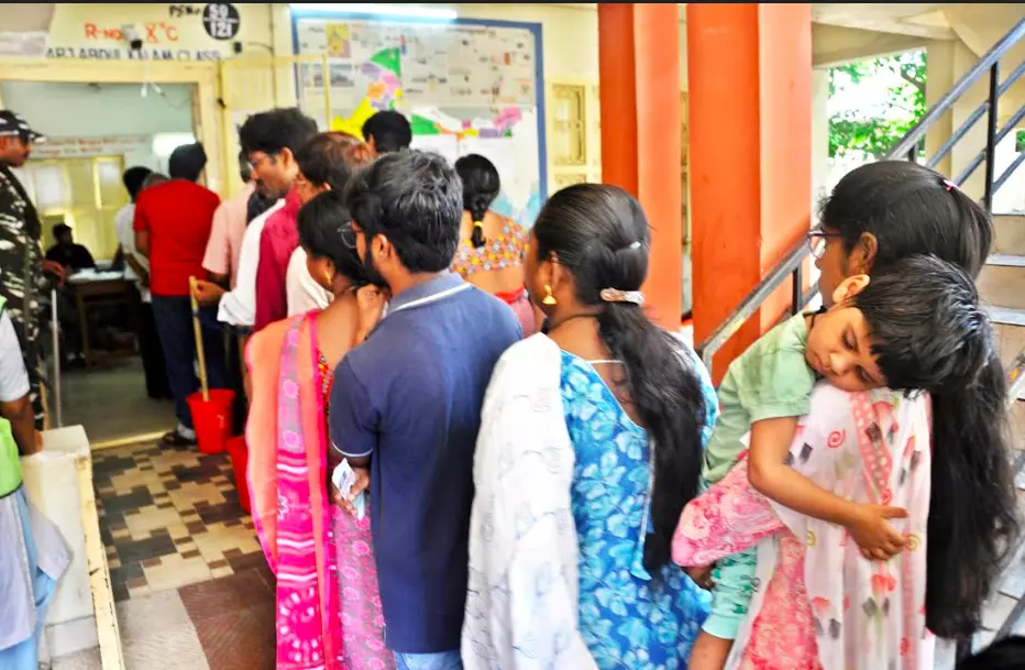 A mother waits in a queue with her kid to cast their vote at Nagaraju Municipal school in Rajamahendravaram on Monday.  - A.MANIKANTA KUMAR