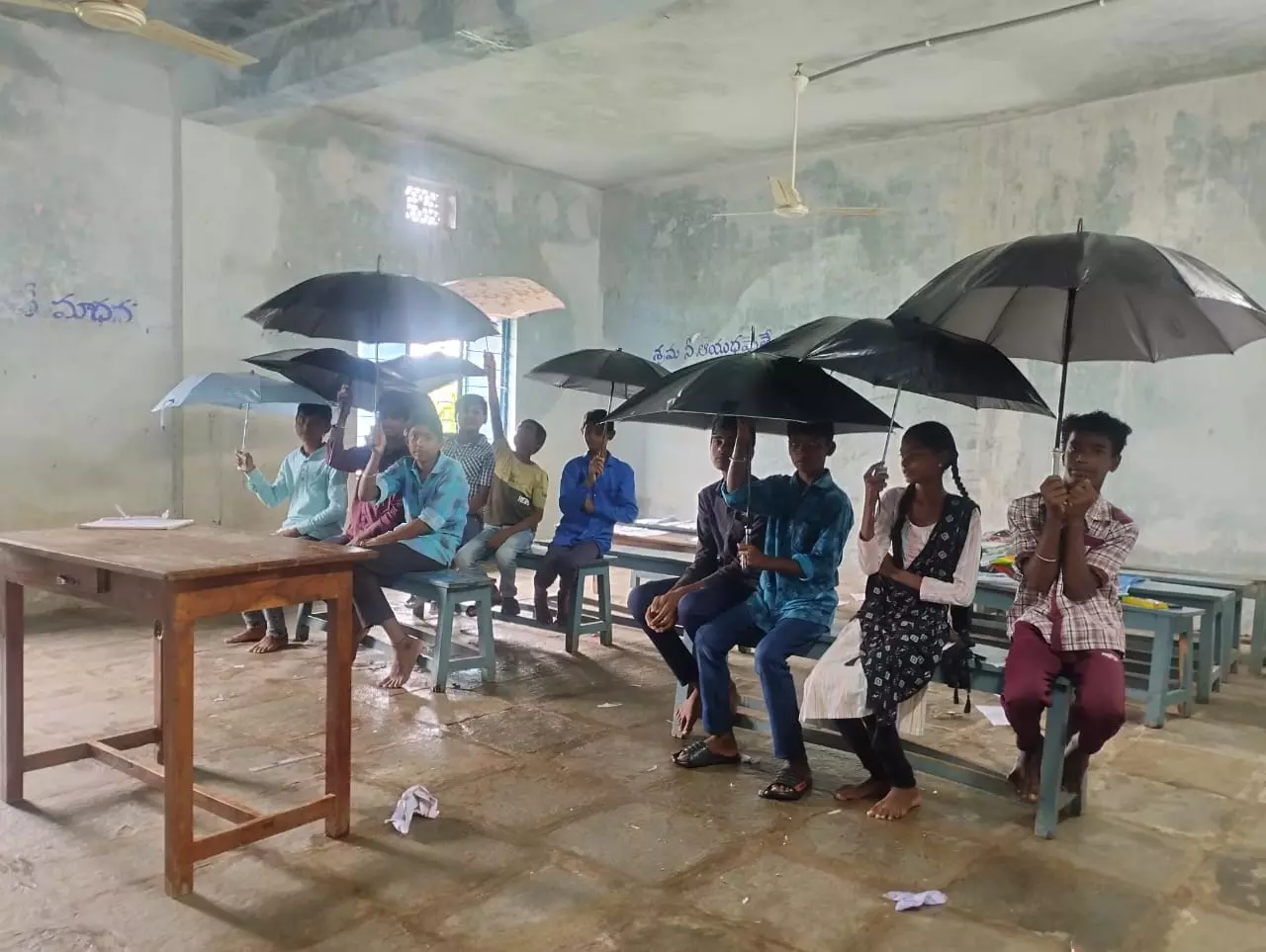 Mancherial: Students protest leaking building by holding umbrellas in classrooms Mancherial: Students protest leaking building by holding umbrellas in classrooms