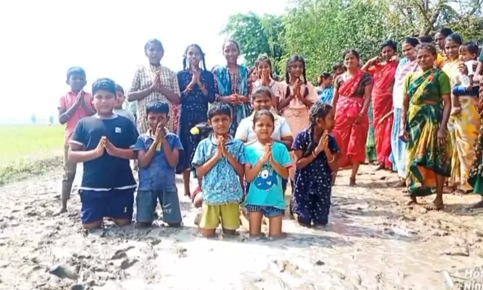 Villagers Kneel in Slushy Mud For Road to Hamlet